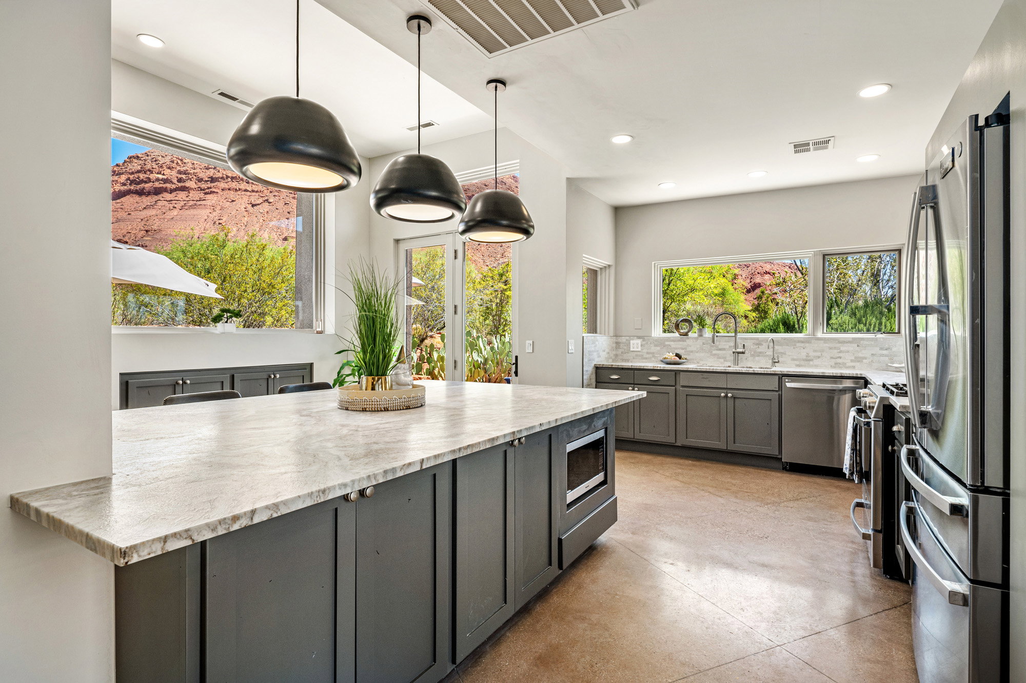 Kitchen featuring a large island with stone countertop, dark cabinetry, and three pendant lights