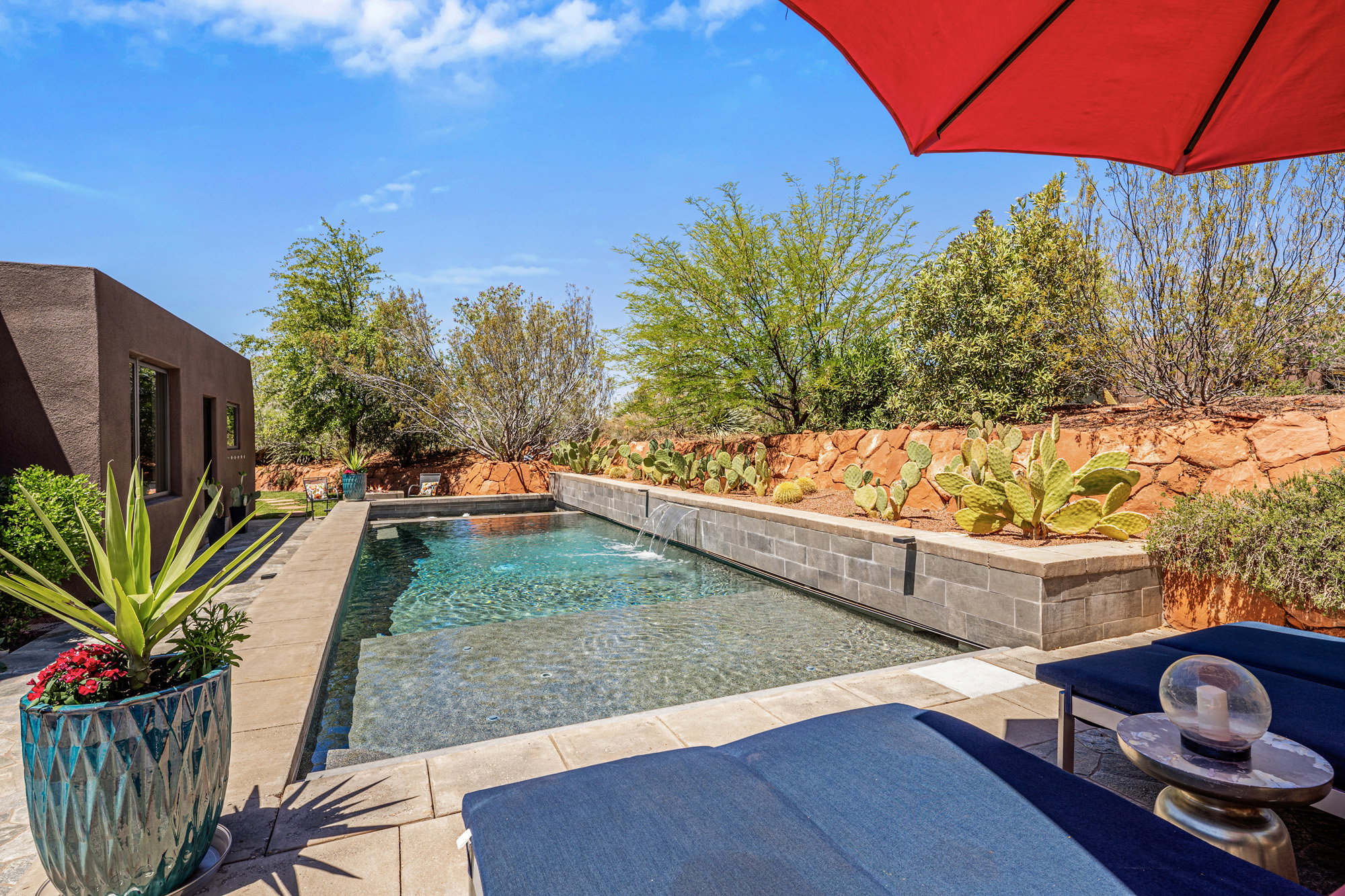 Outdoor swimming pool featuring a water feature, surrounding patio, and desert landscaping