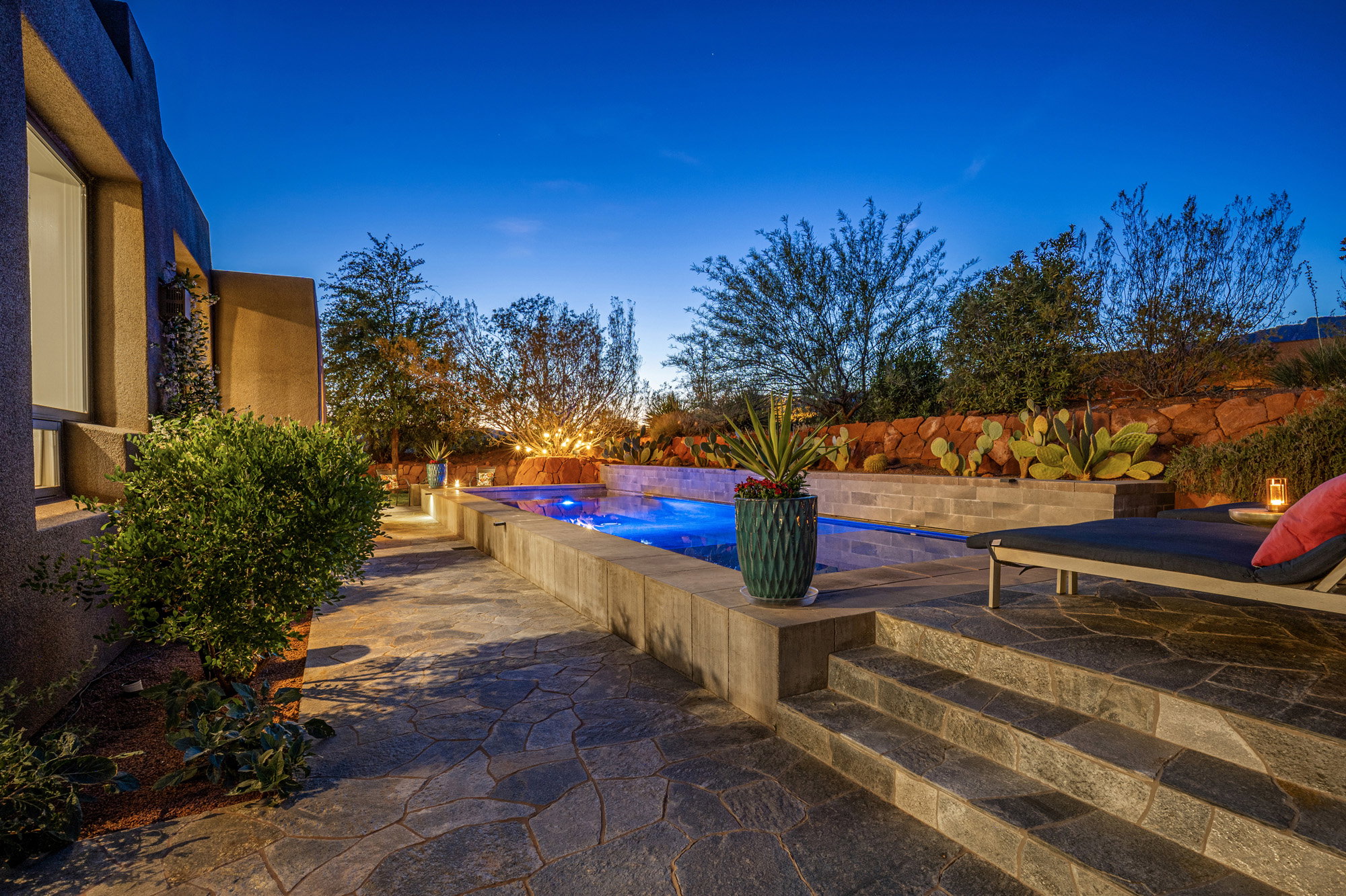 Outdoor living area featuring a custom pool with illuminated water, flagstone patio, and integrated steps