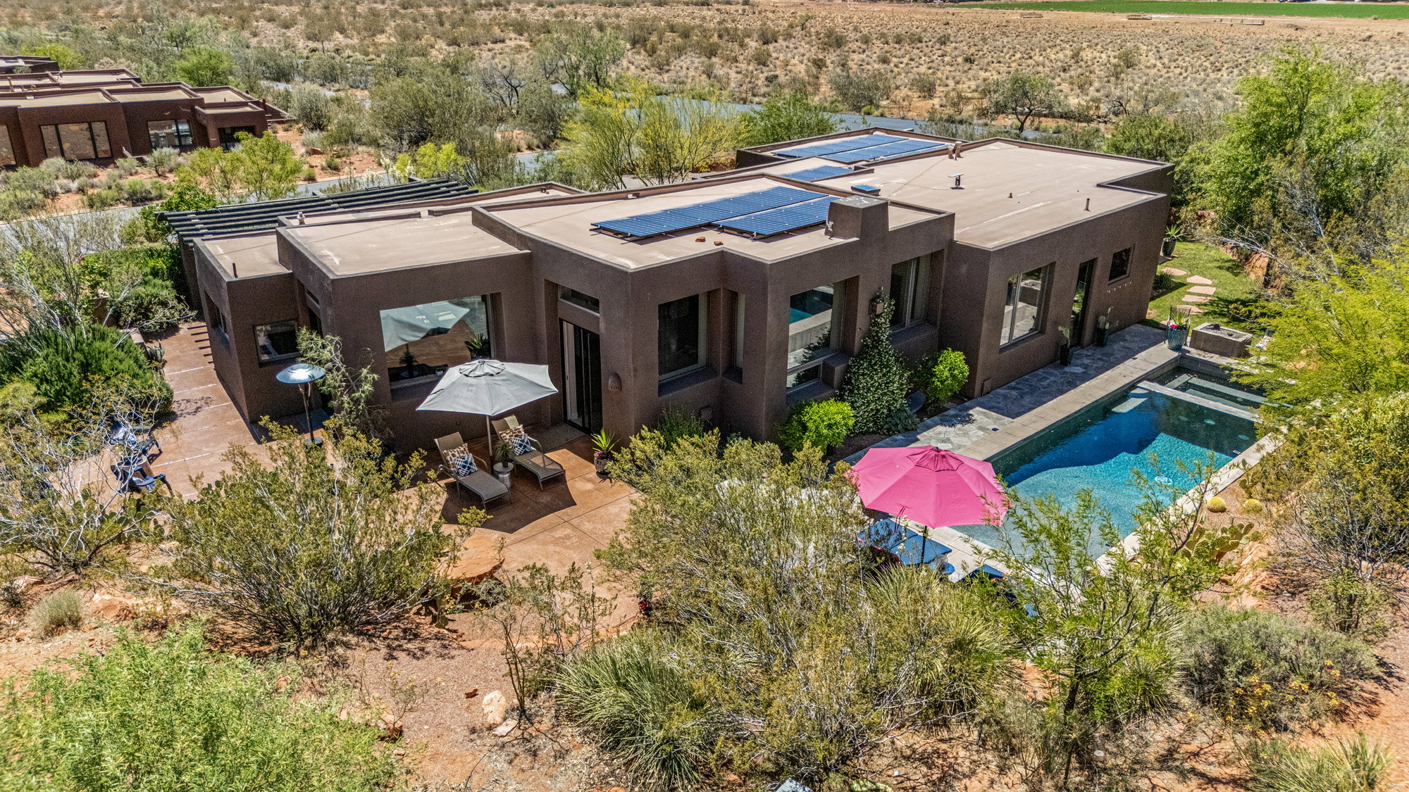 Modern stucco exterior with a flat roof, featuring multiple solar panels and large windows