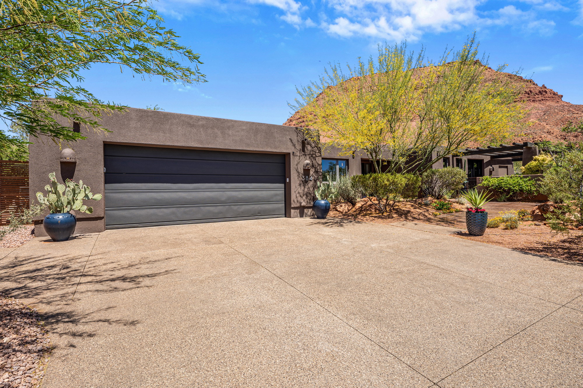 Desert contemporary residence featuring a stucco exterior and a dark paneled garage door