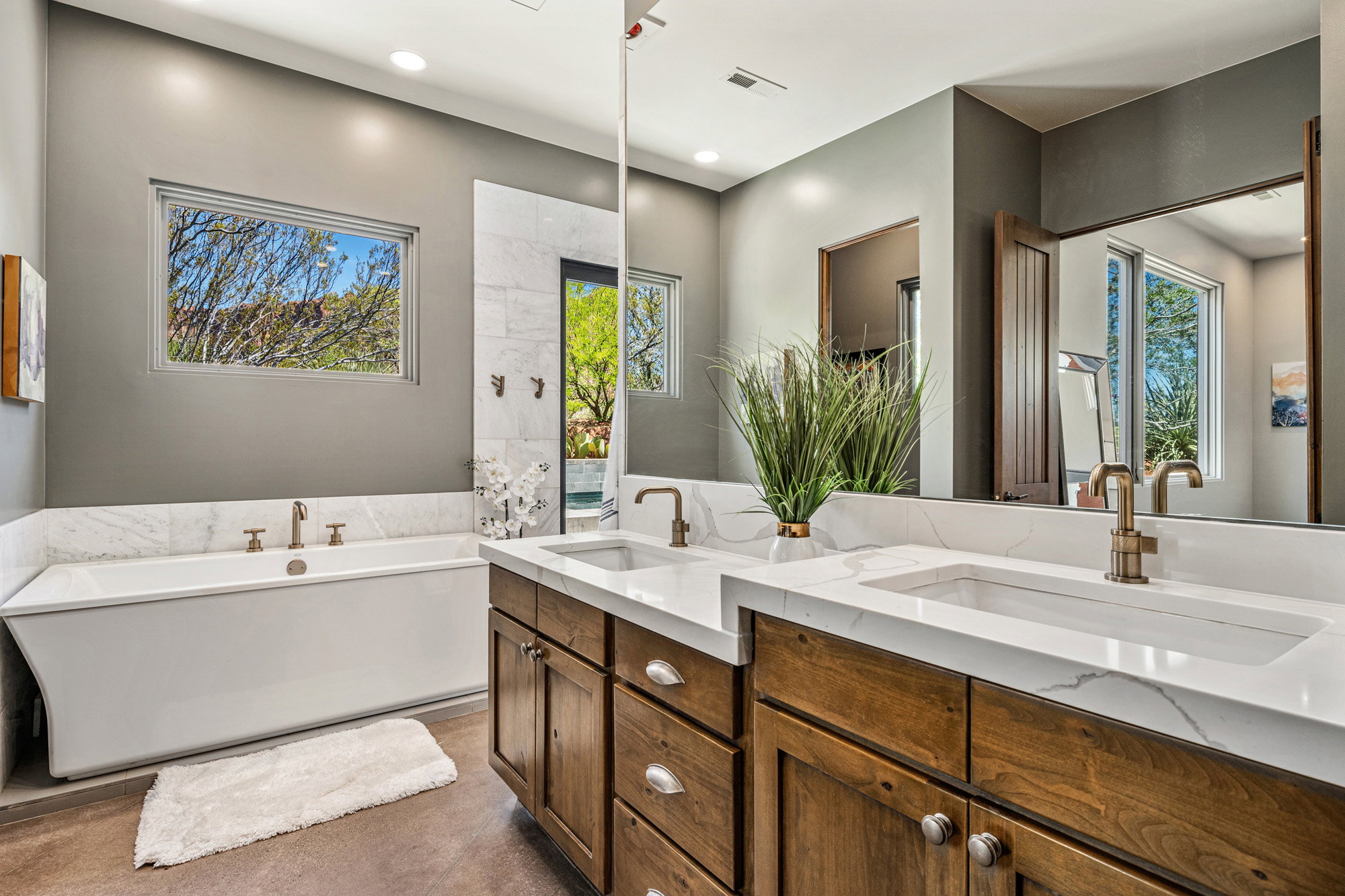 Bathroom featuring a freestanding soaking tub, dual vanity with undermount sinks, and stone countertops