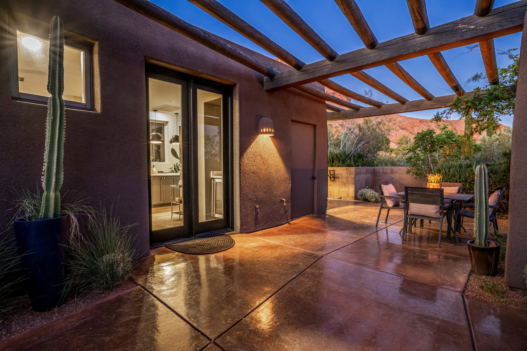 Spacious outdoor patio featuring a wood-beam pergola, durable concrete flooring, and a stone retaining wall