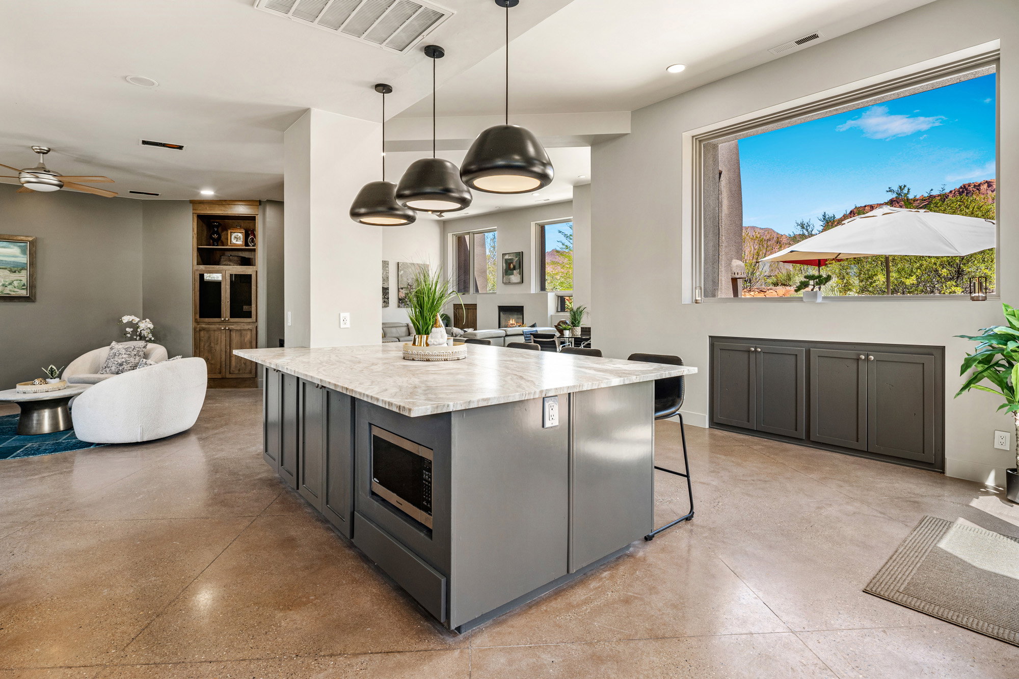 Kitchen island with a light-toned countertop, integrated microwave, and pendant lighting