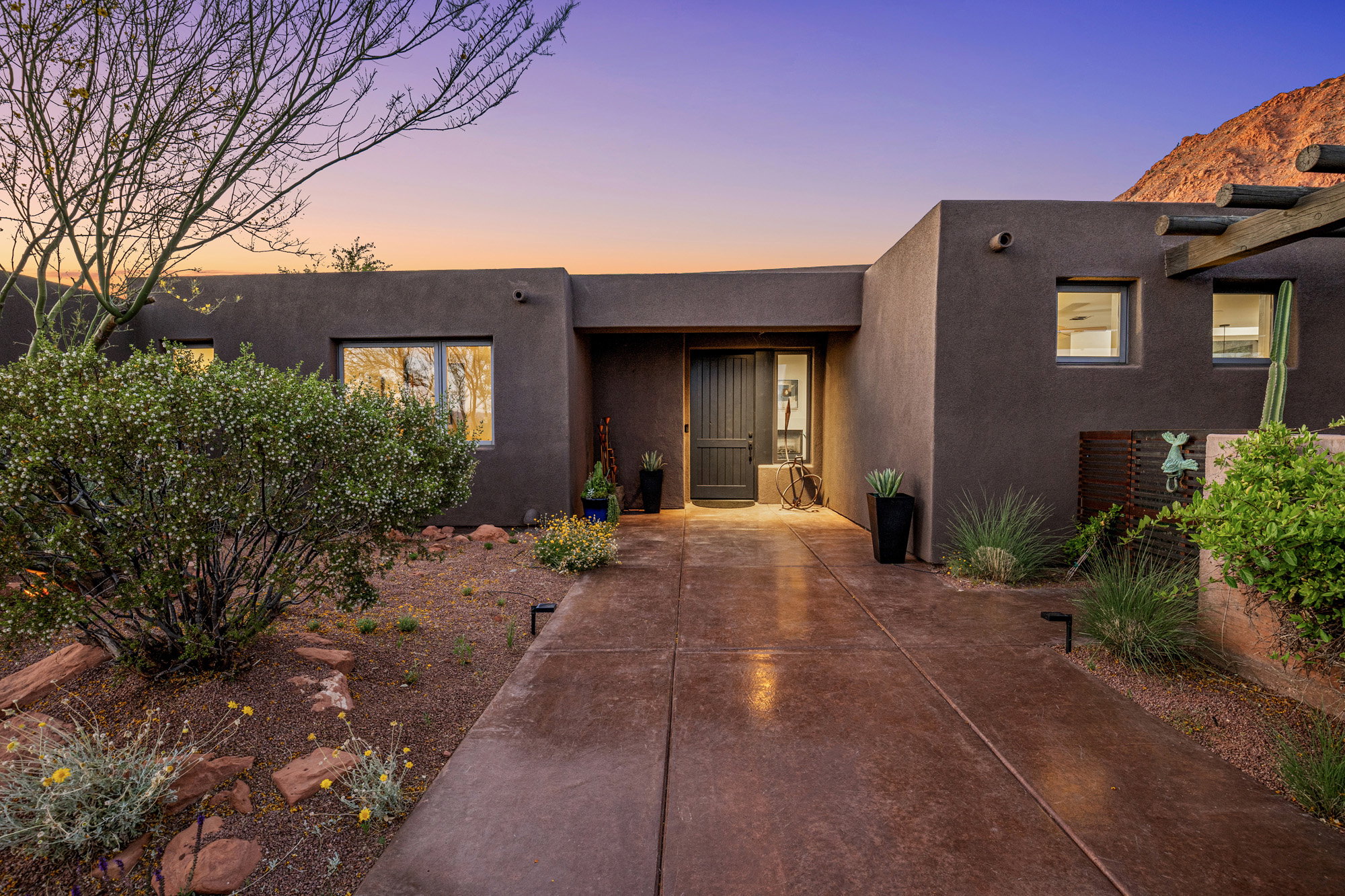 Contemporary stucco exterior with a prominent entry door, surrounded by desert landscaping and a concrete walkway