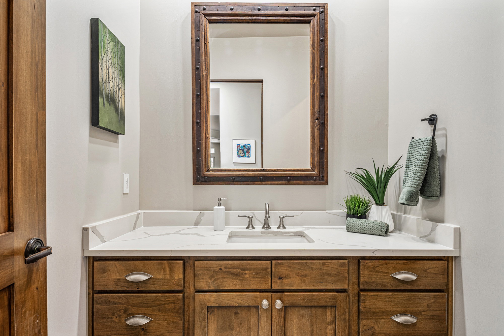 Bathroom vanity featuring a rectangular undermount sink, a stone-finish countertop with veining, wood cabinetry, and a framed mirror