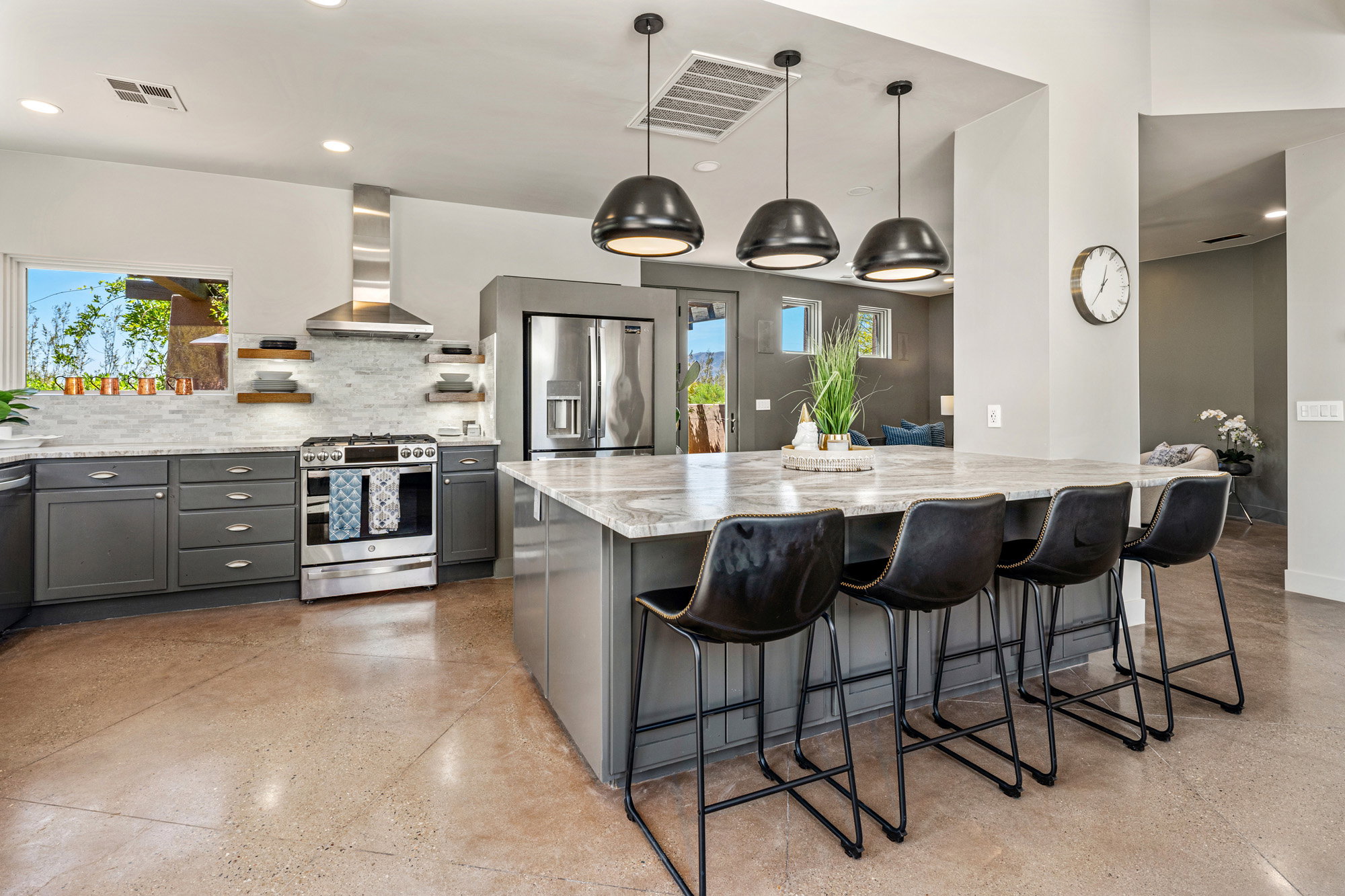 Modern kitchen featuring an expansive center island with seating, stainless steel appliances, and sleek gray cabinetry