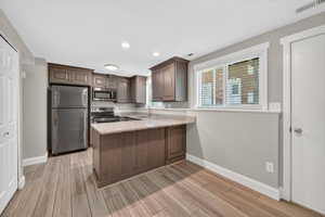 Kitchen featuring wood-finish flooring, granite countertops, stainless steel appliances, recessed lighting, and a breakfast bar