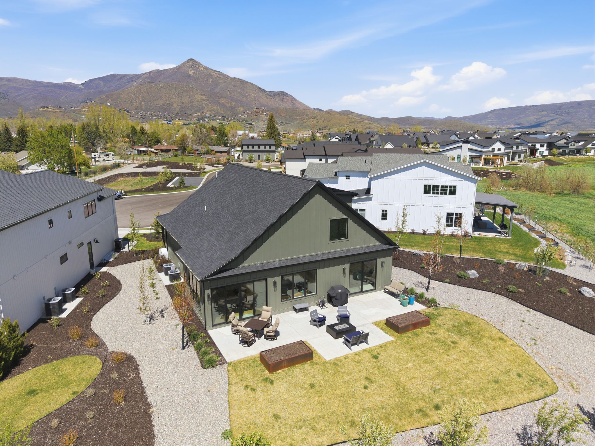 Contemporary residential exterior featuring a dark green facade with a black asphalt shingle roof
