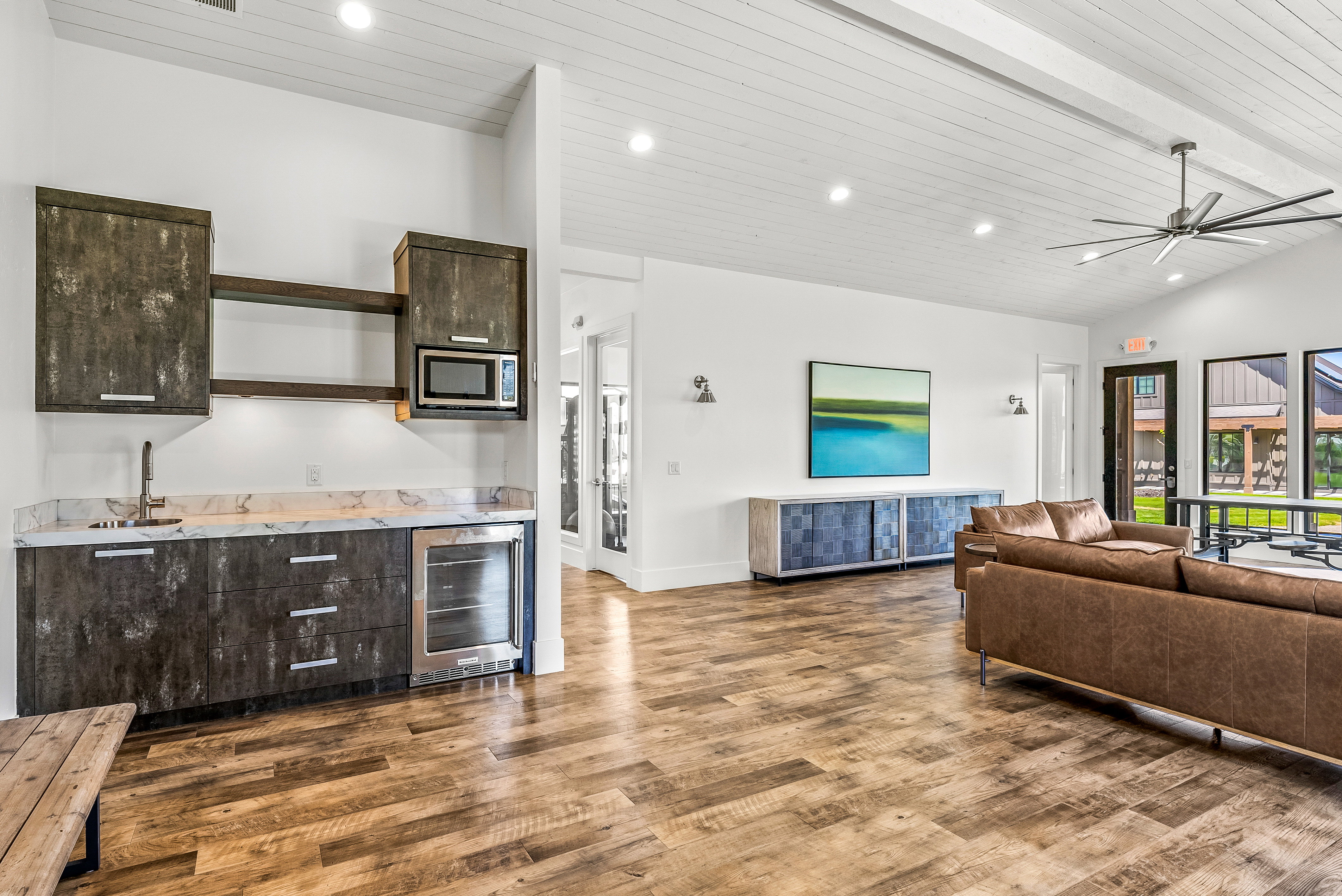 Open concept room featuring a wet bar with dark-finish cabinetry, a built-in microwave, and a beverage refrigerator