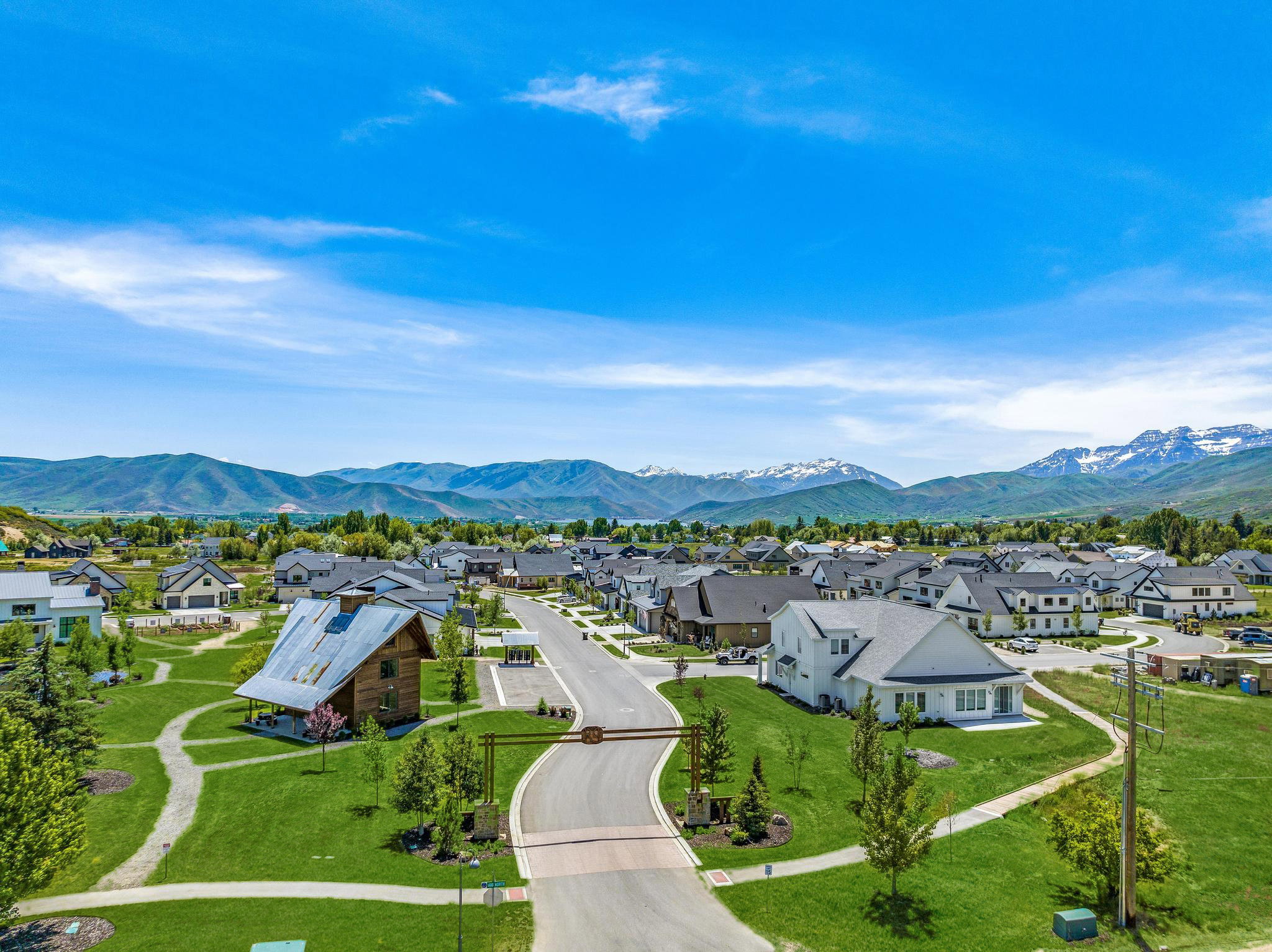 Aerial perspective of a developed residential community featuring an organized street grid, mature green spaces, and snow-capped mountain backdrop