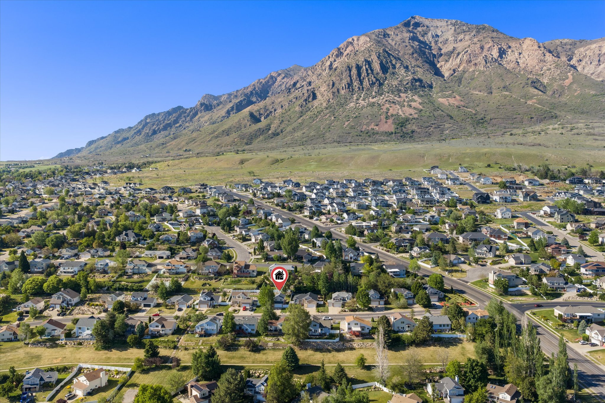 Aerial perspective of a residential community with abundant mature trees and mountainous terrain
