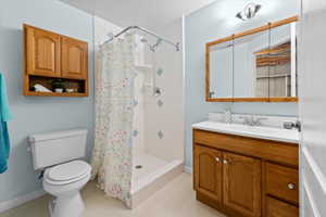 Bathroom with a single vanity, white countertop, chrome faucet, and wood-finish cabinetry