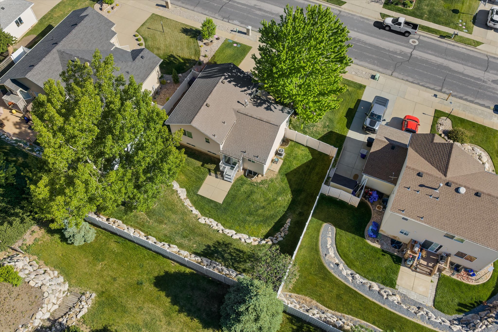 Rear yard featuring a manicured lawn, established trees, a concrete patio, and a privacy fence