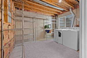Laundry area featuring a window, bare concrete walls, exposed ceiling joists, and light gray carpeting