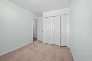 Carpeted room featuring light green walls, white baseboards, and bi-fold closet doors with panel detailing