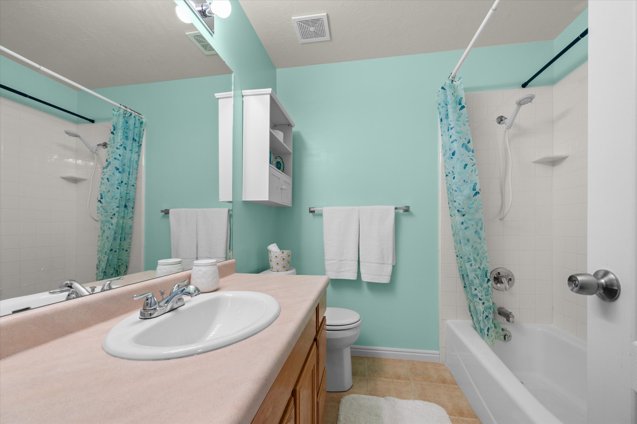 Bathroom featuring a single vanity with an oval sink, chrome faucet, and wood-finish cabinetry