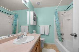 Bathroom featuring a single vanity with an oval sink, chrome faucet, and wood-finish cabinetry