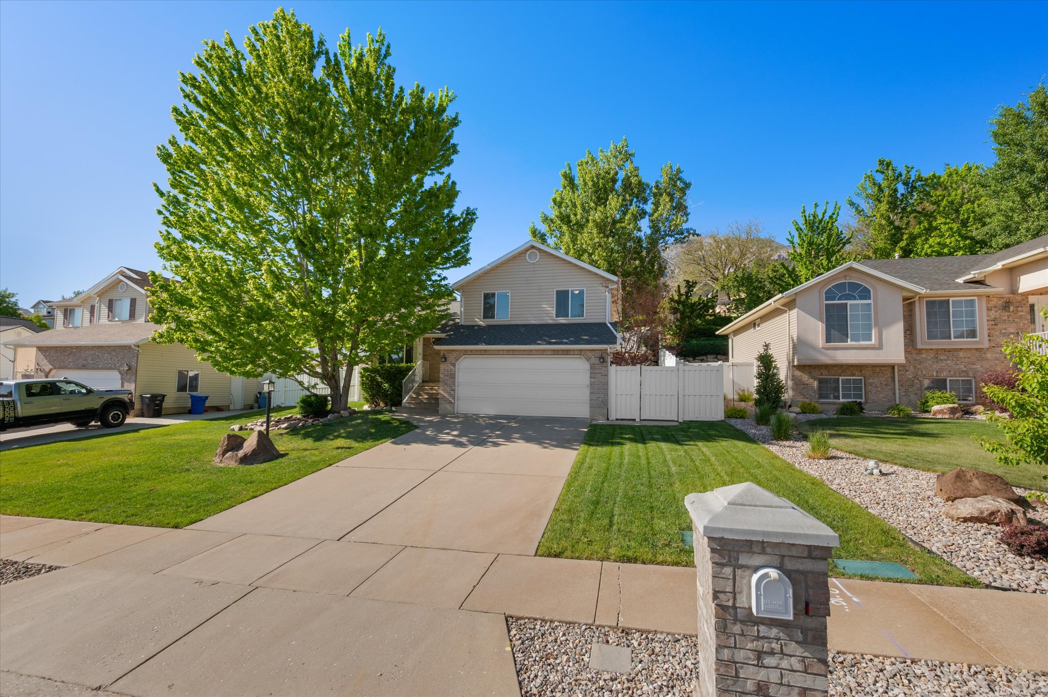 Tri-multi level  residence featuring a two-car garage, mature landscaping, and an extended concrete driveway
