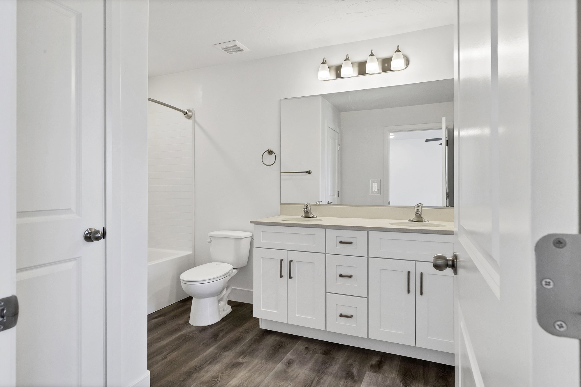 Bathroom featuring a dual vanity with white cabinetry, light-toned countertop, and undermount sinks