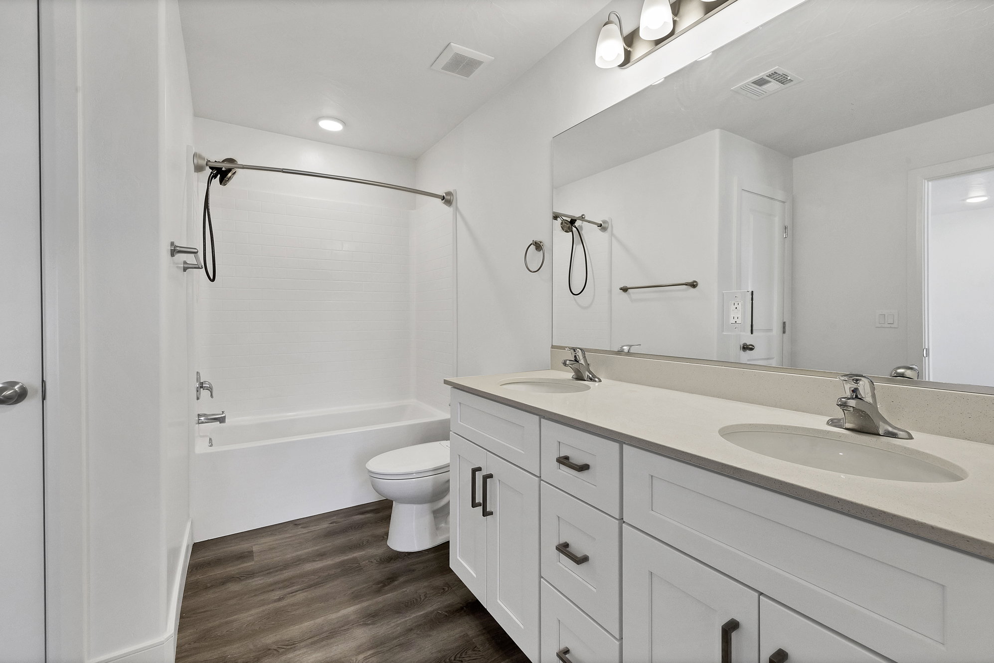 Bathroom featuring a dual-sink vanity with light-toned countertops, white cabinetry, and brushed nickel hardware