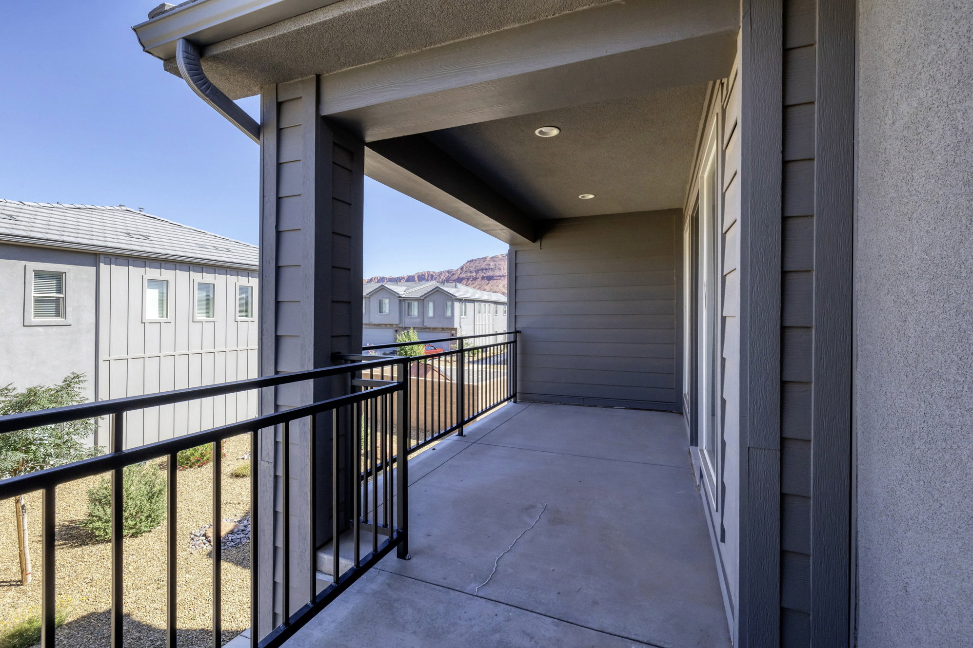 Covered balcony featuring concrete flooring, black metal railings, and recessed lighting