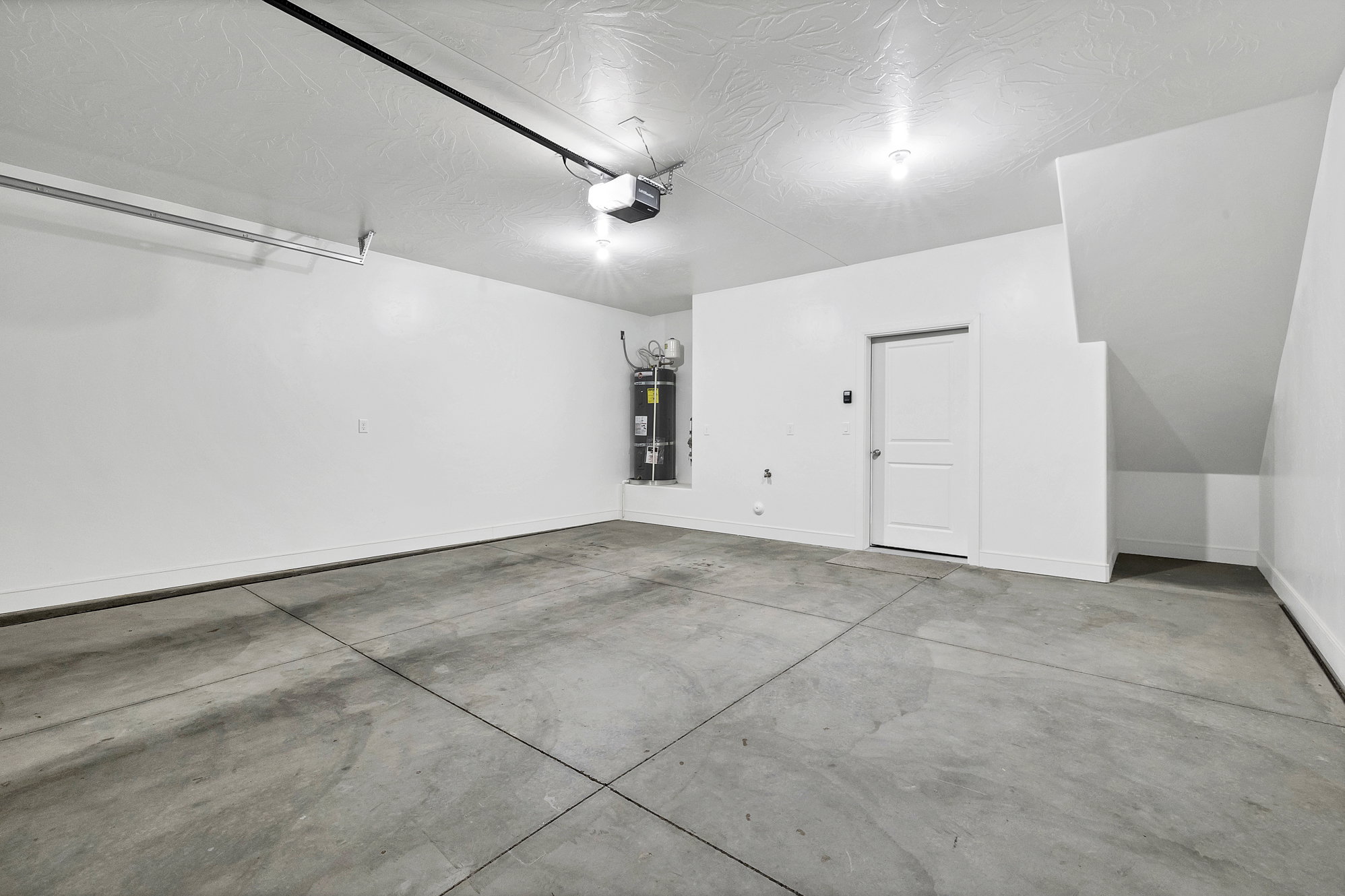 Spacious garage featuring a concrete floor, painted walls, and an overhead garage door opener