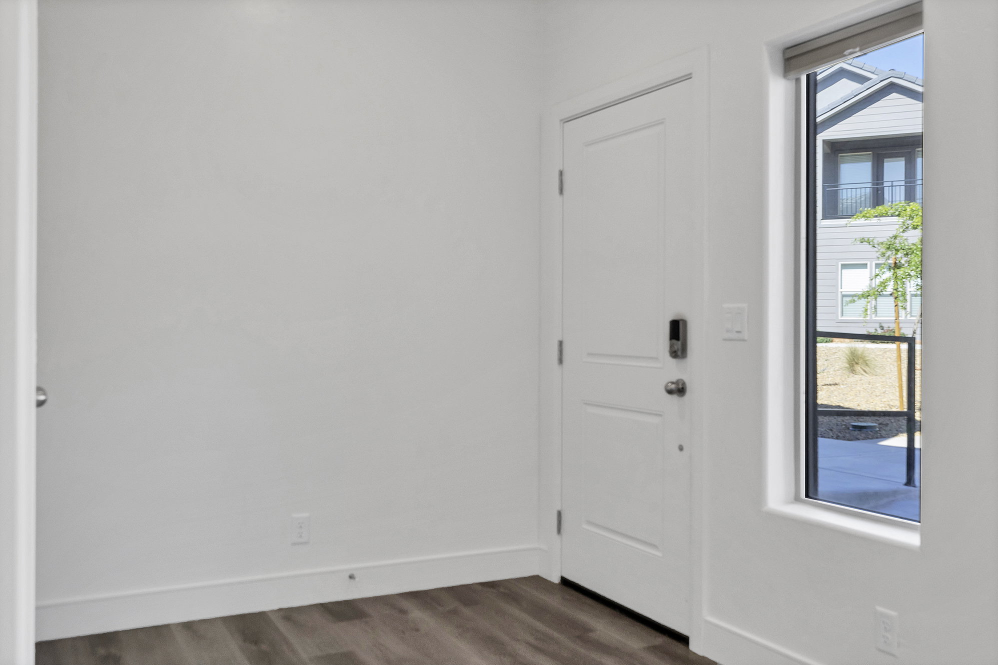 Entryway featuring wood-finish flooring and a contemporary white door with smart lock