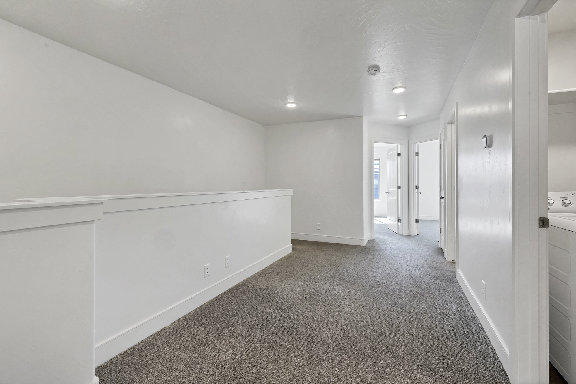 Carpeted loft area featuring white walls, recessed lighting, and white baseboards