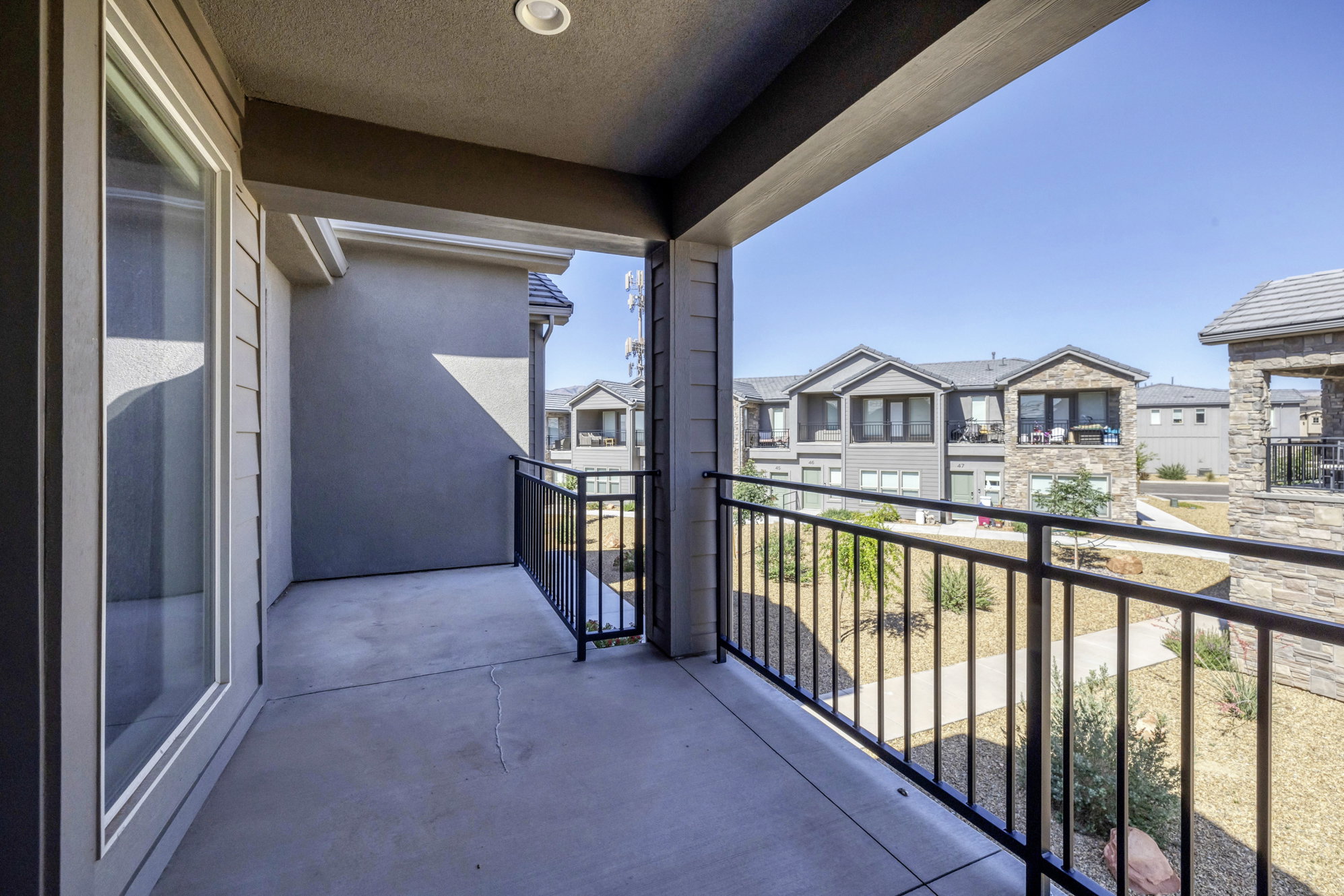 Covered outdoor patio with concrete flooring, recessed lighting, and black metal railings