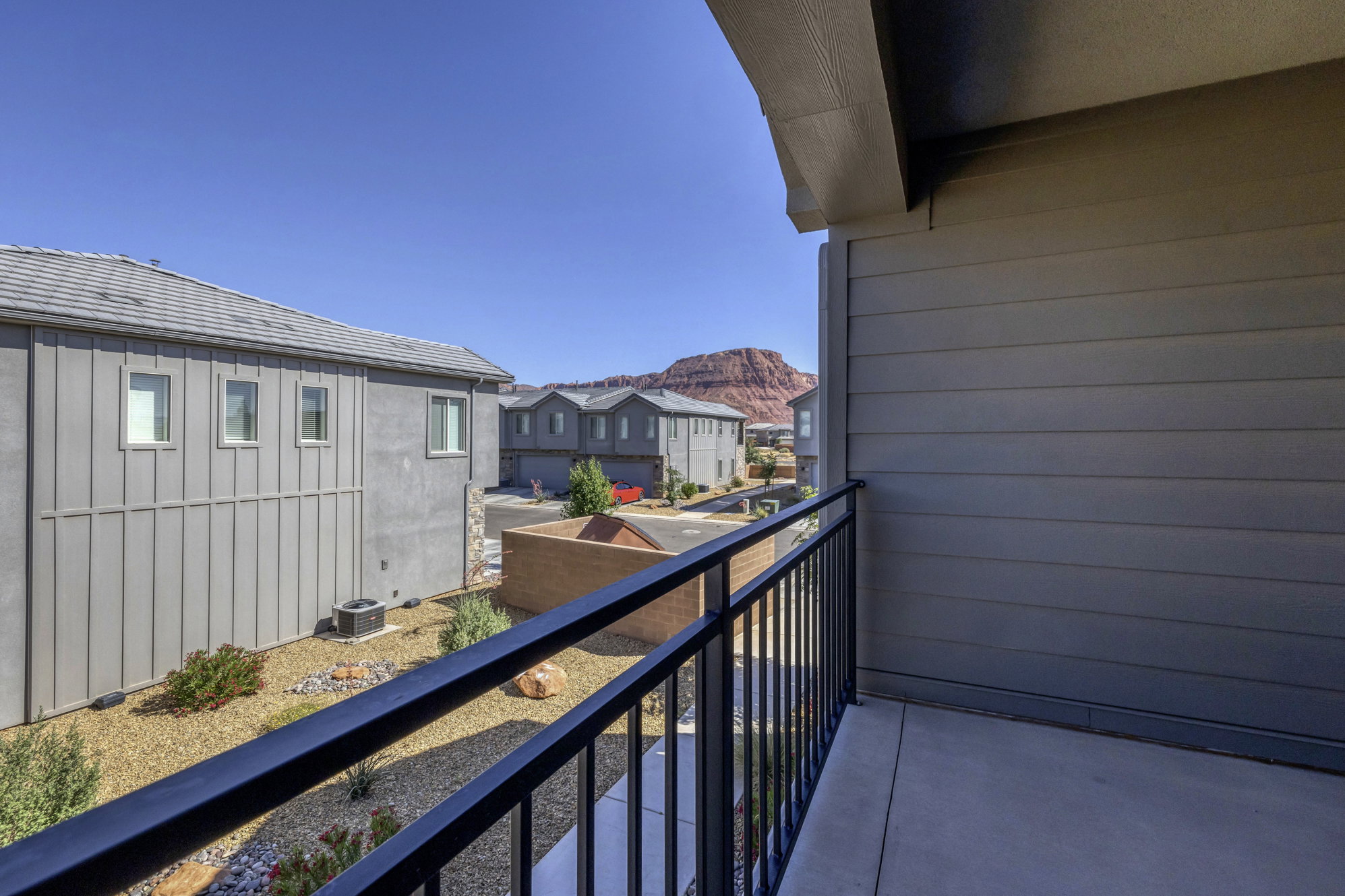 Private outdoor balcony with concrete flooring and dark metal railings