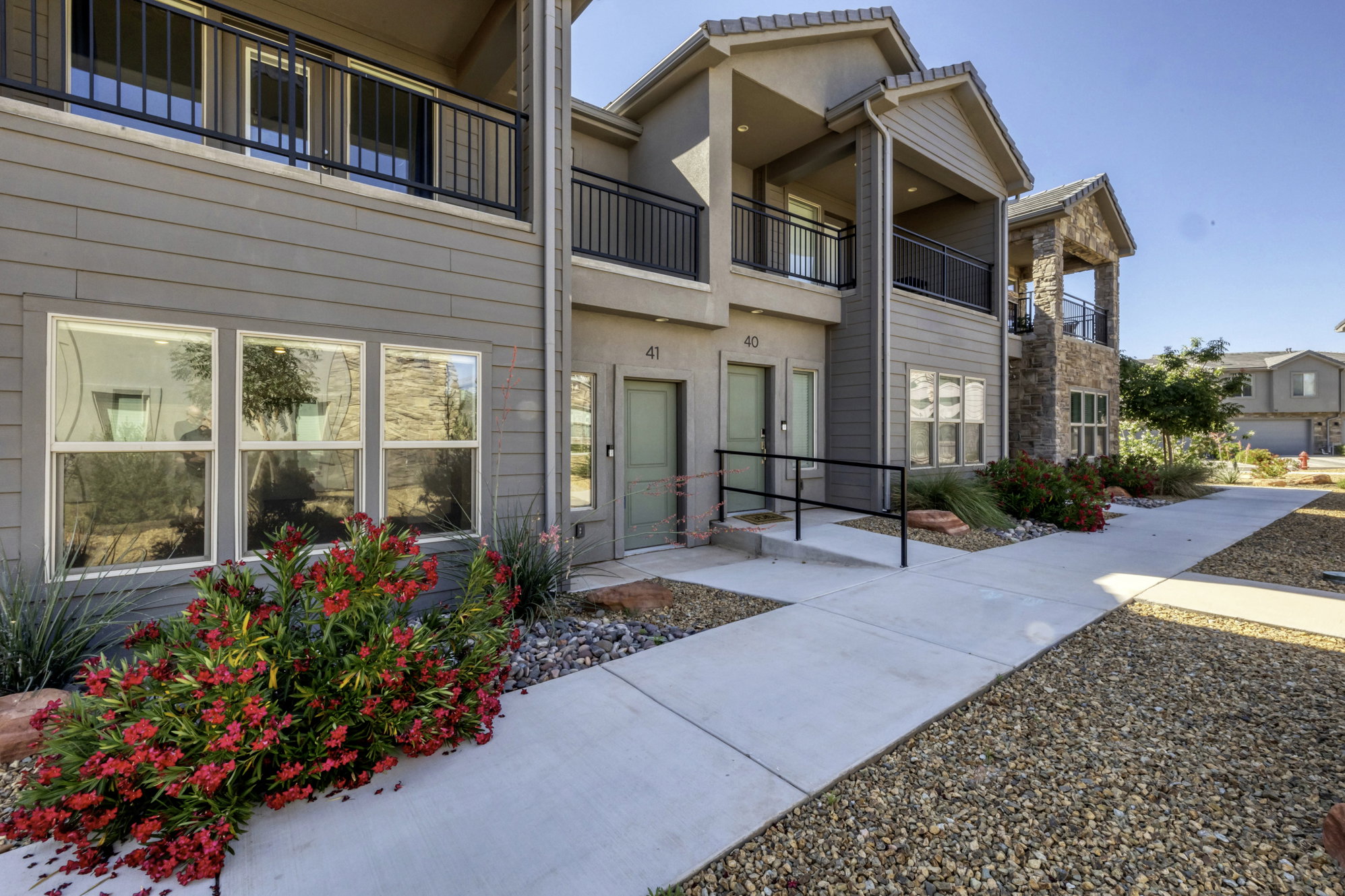 Contemporary multi-story exterior with horizontal siding, stone accents, and covered balconies featuring black railings