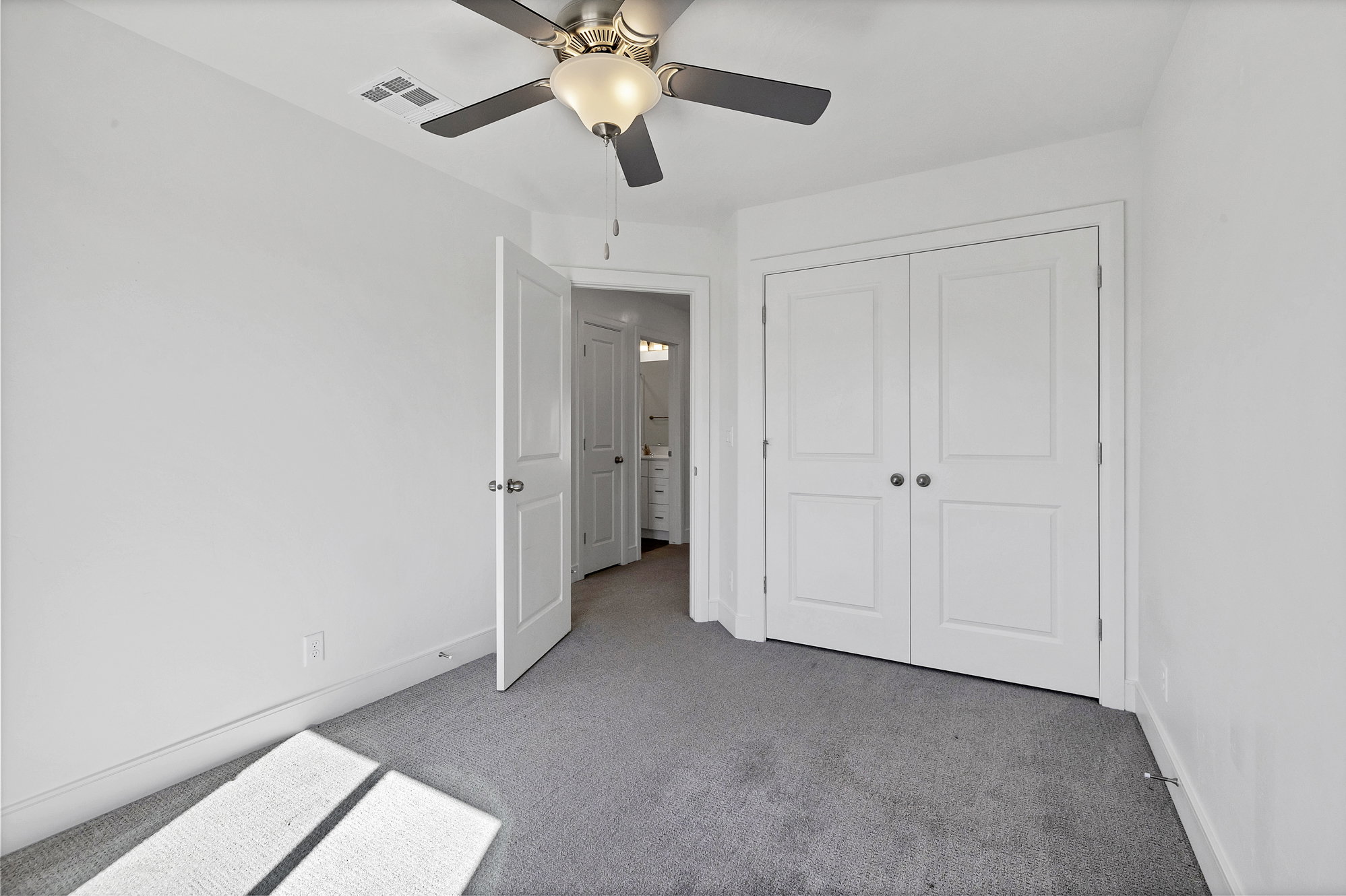 Neutral tone carpeting complementing white walls, with a ceiling fan overhead