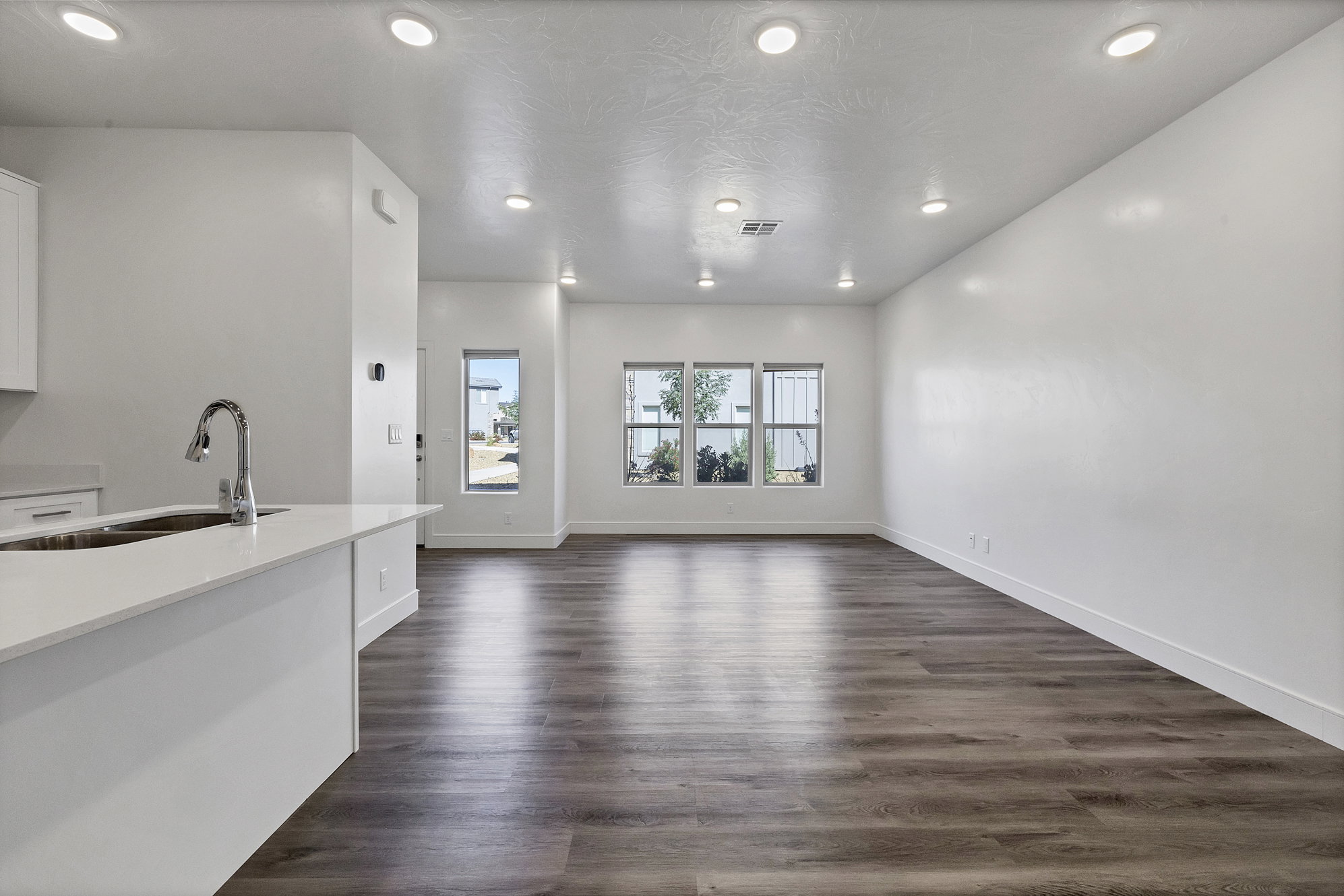 Open-concept living area with wood-finish flooring, recessed lighting, and multiple windows