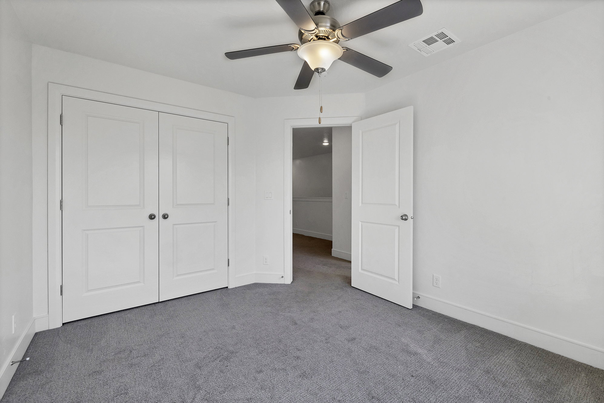 Spacious room featuring plush gray carpeting and white walls