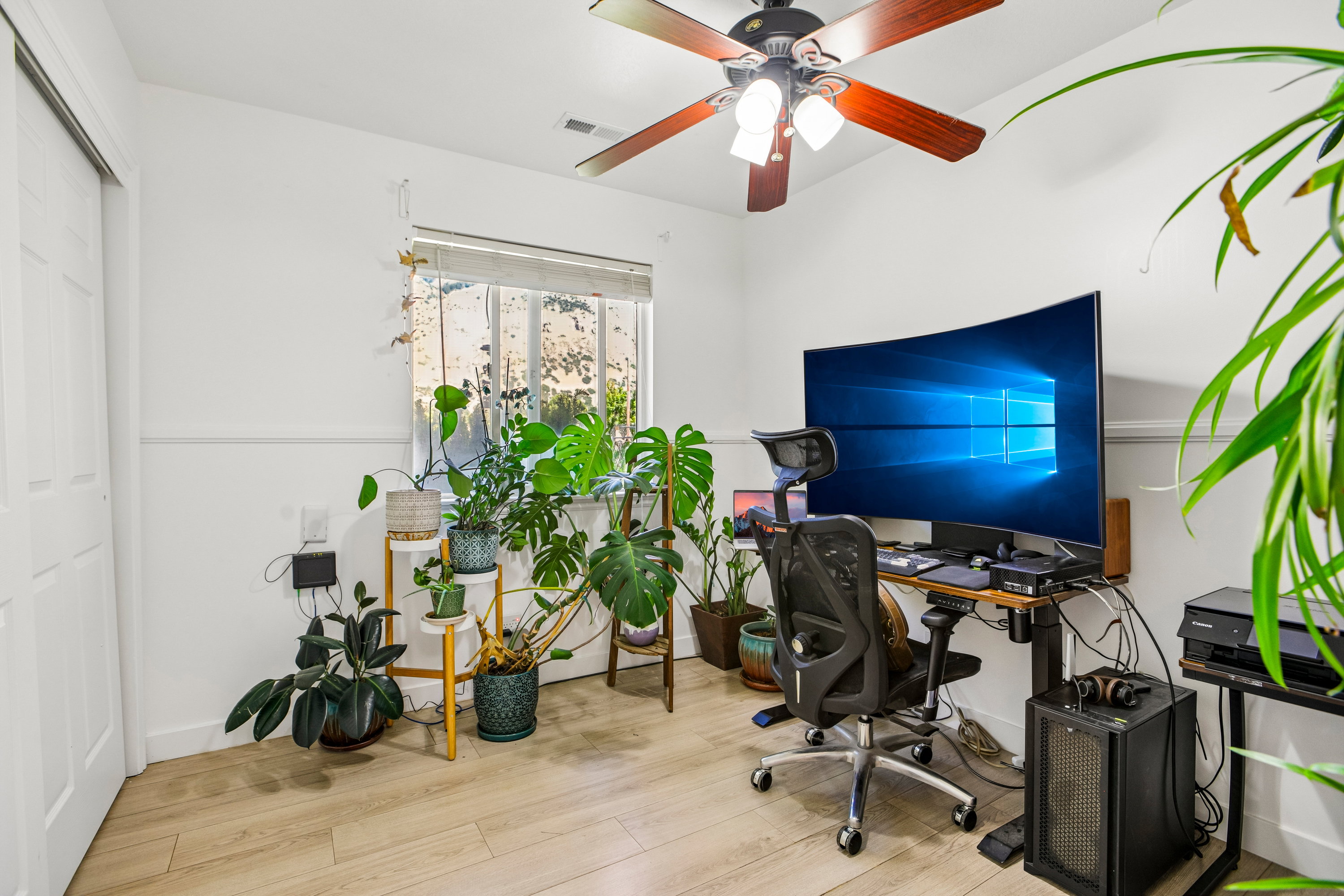 Room featuring wood-finish flooring, white walls with wainscoting, and a window with blinds
