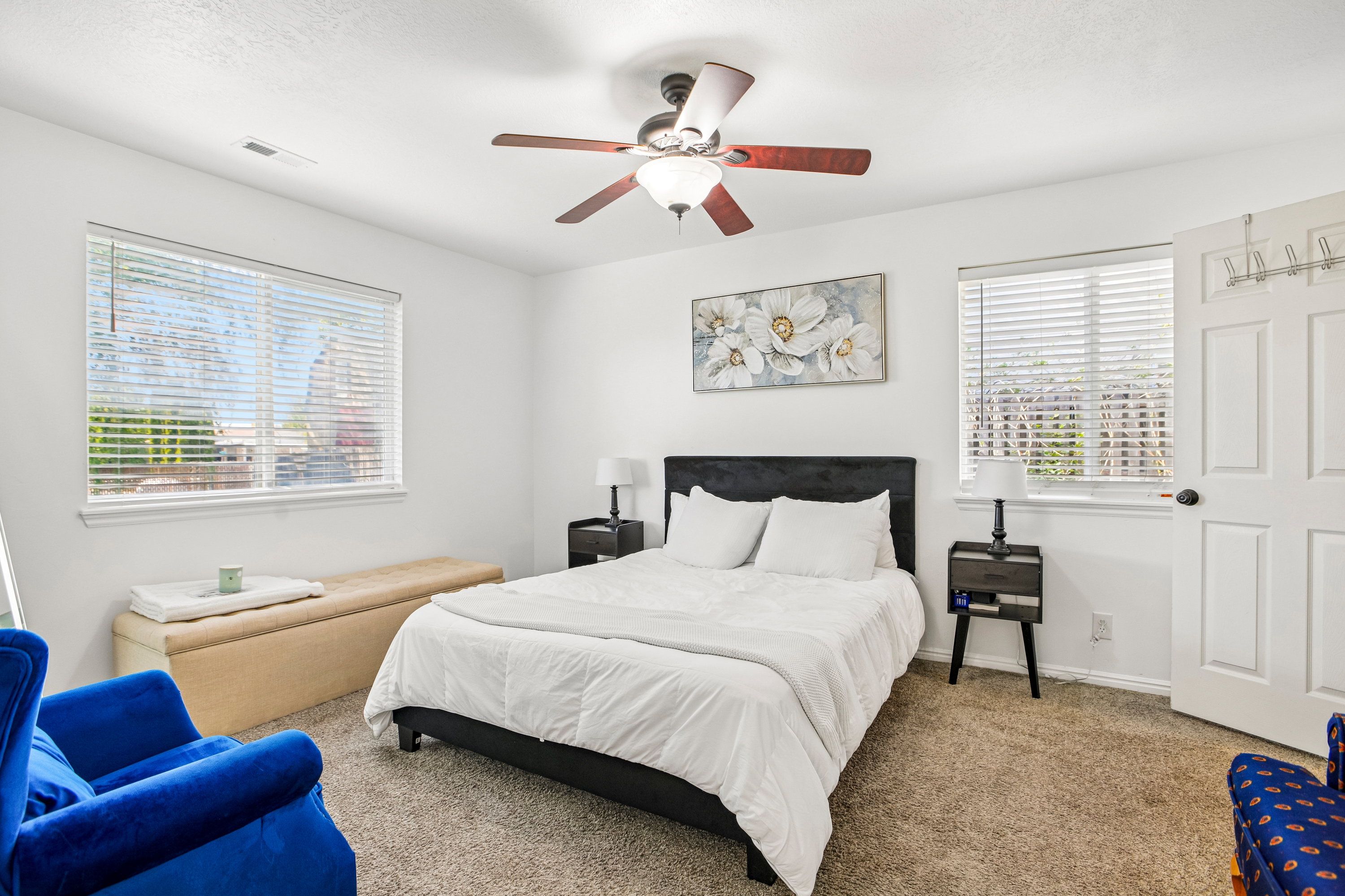 Bedroom with two windows featuring blinds, a ceiling fan with light fixture, and neutral carpet flooring