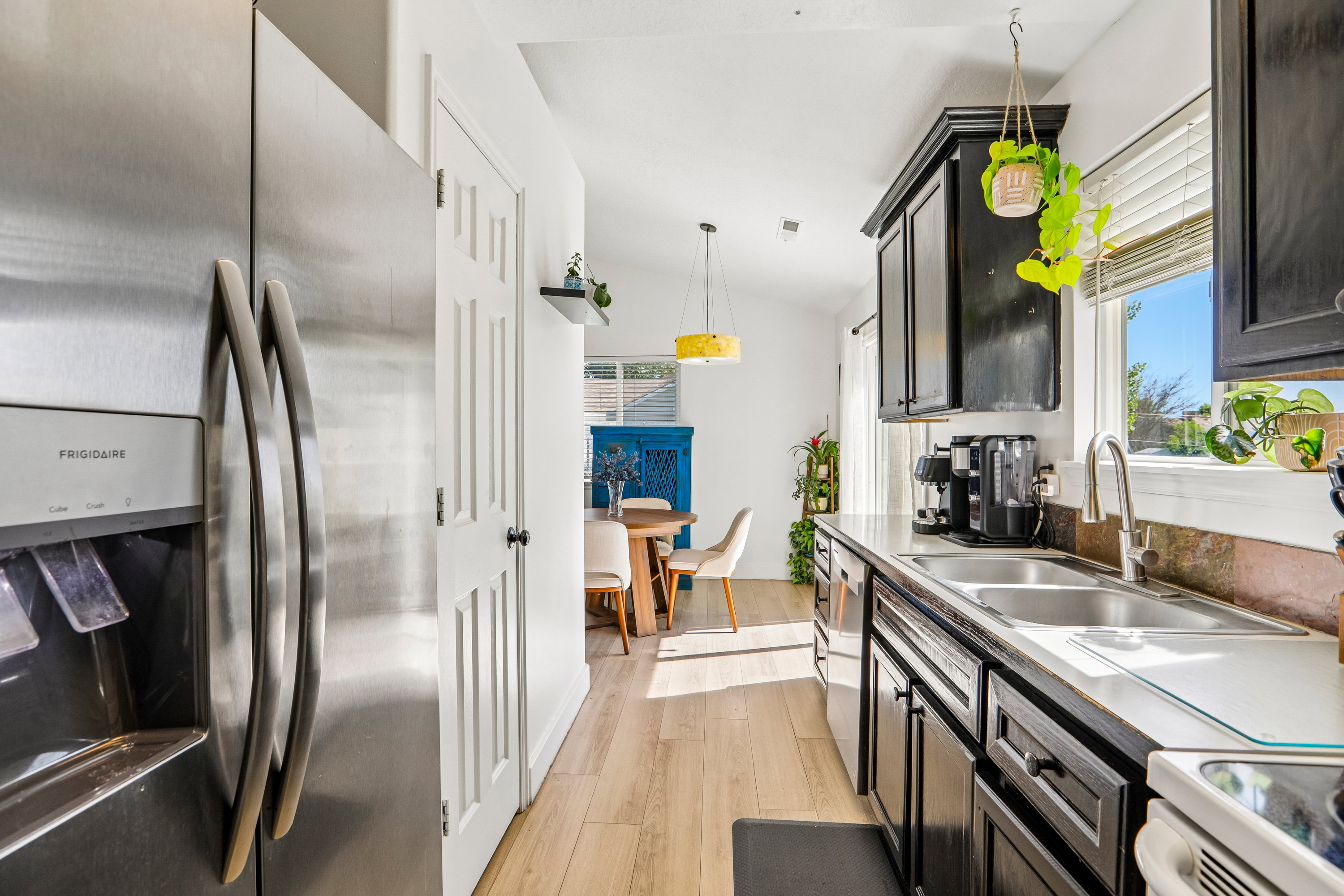 Kitchen featuring black cabinetry, stainless steel sink, and wood-finish flooring