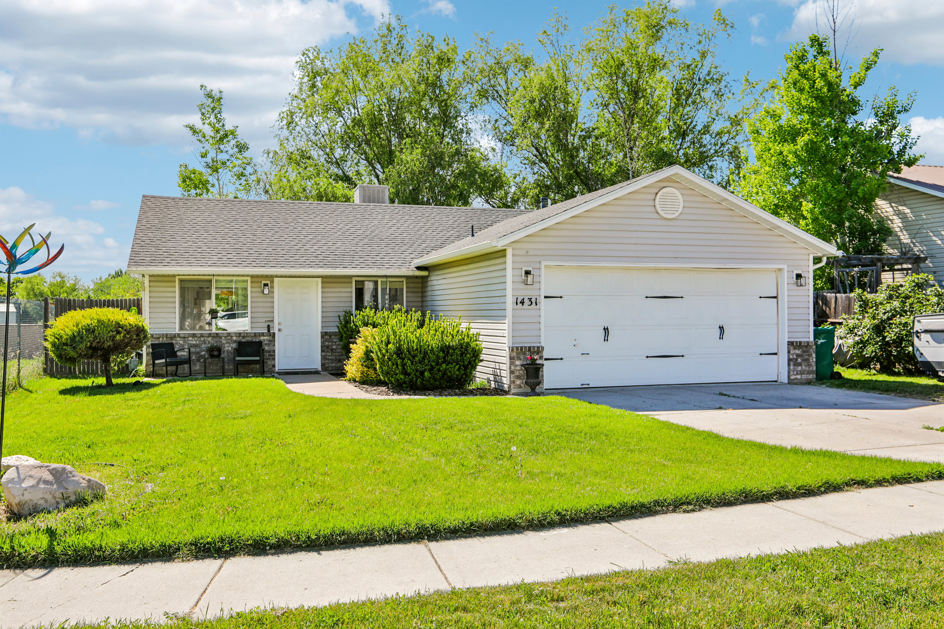 Ranch-style residence featuring light-colored siding and a two-car garage