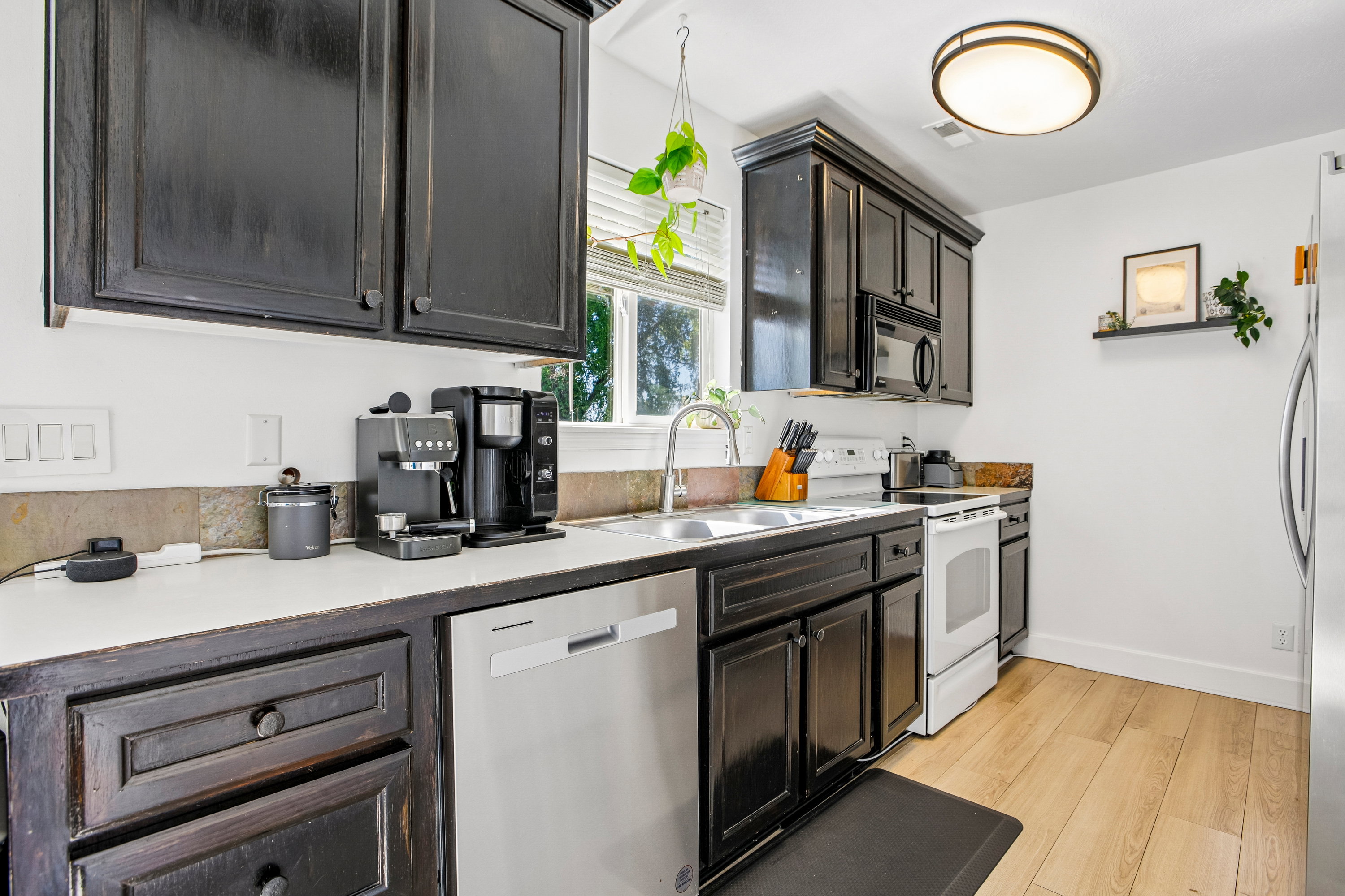 Kitchen featuring dark wood cabinetry, light countertops, and a stone-finish backsplash