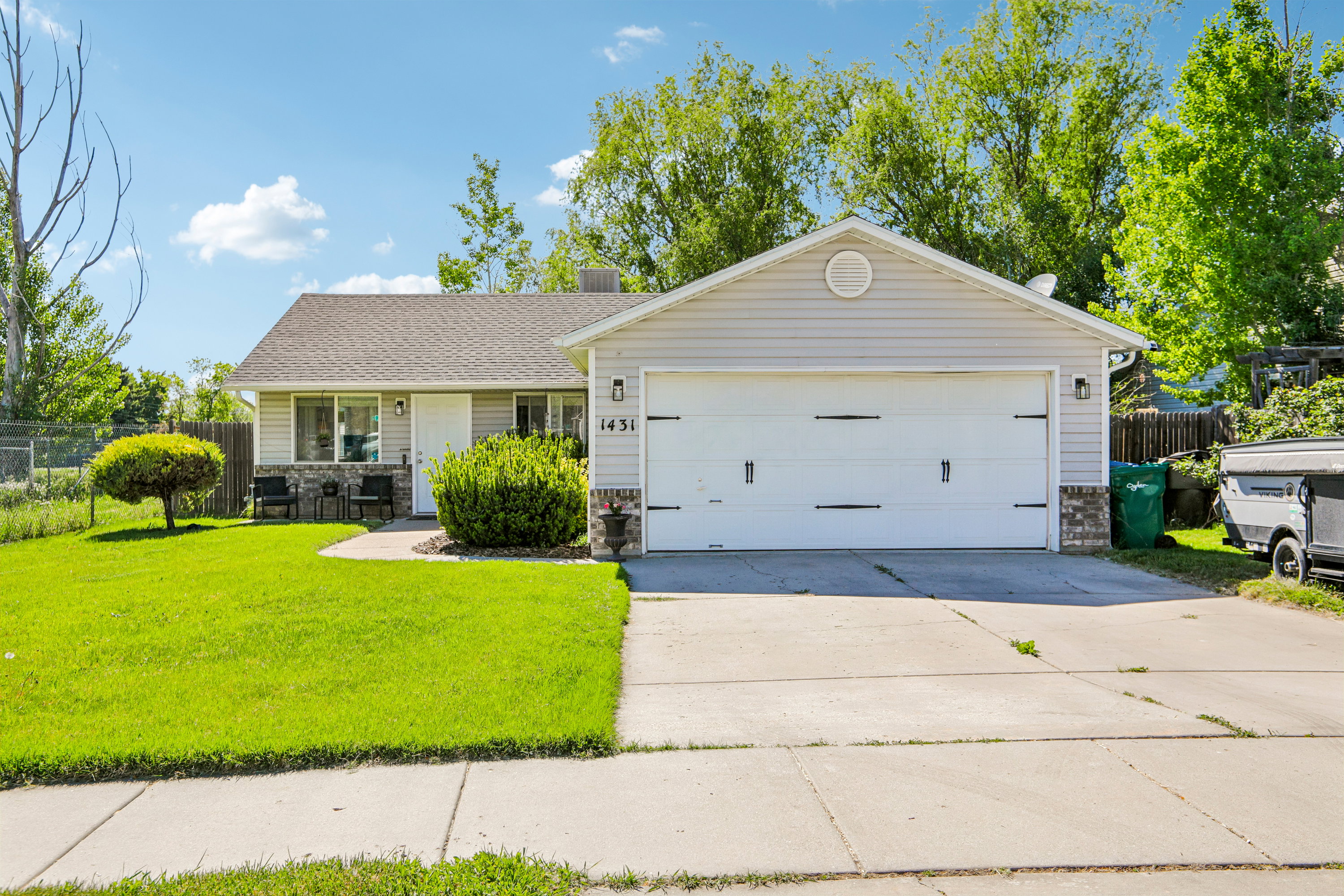 Ranch-style residence featuring a two-car garage, concrete driveway, and front lawn