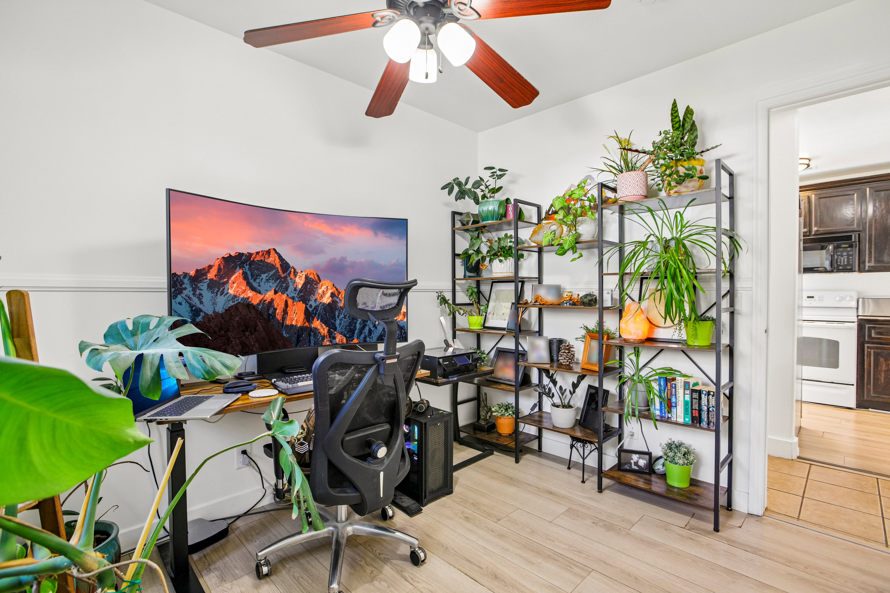 Room featuring wood-finish flooring, a ceiling fan with light fixture, and white wall paint