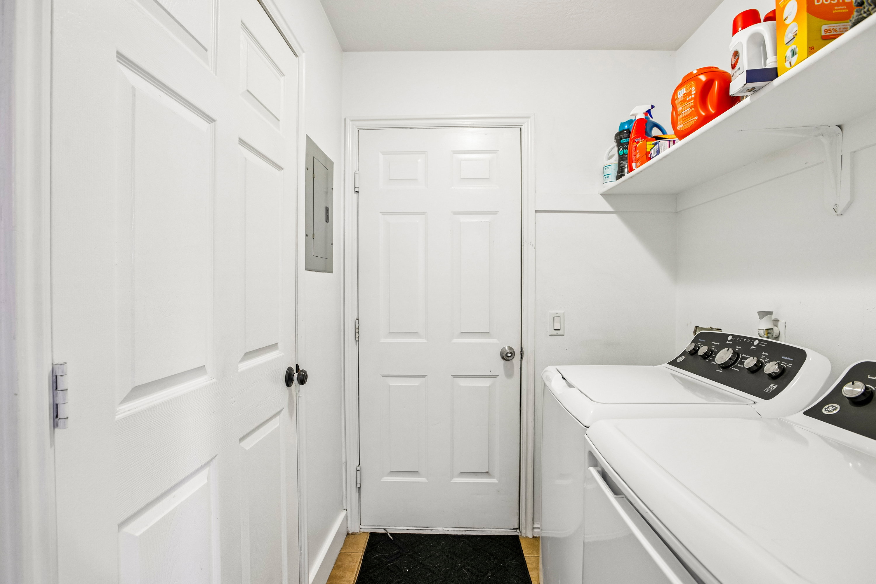 Dedicated utility area featuring a paneled door, built-in shelving, white appliances, and wood-finish flooring