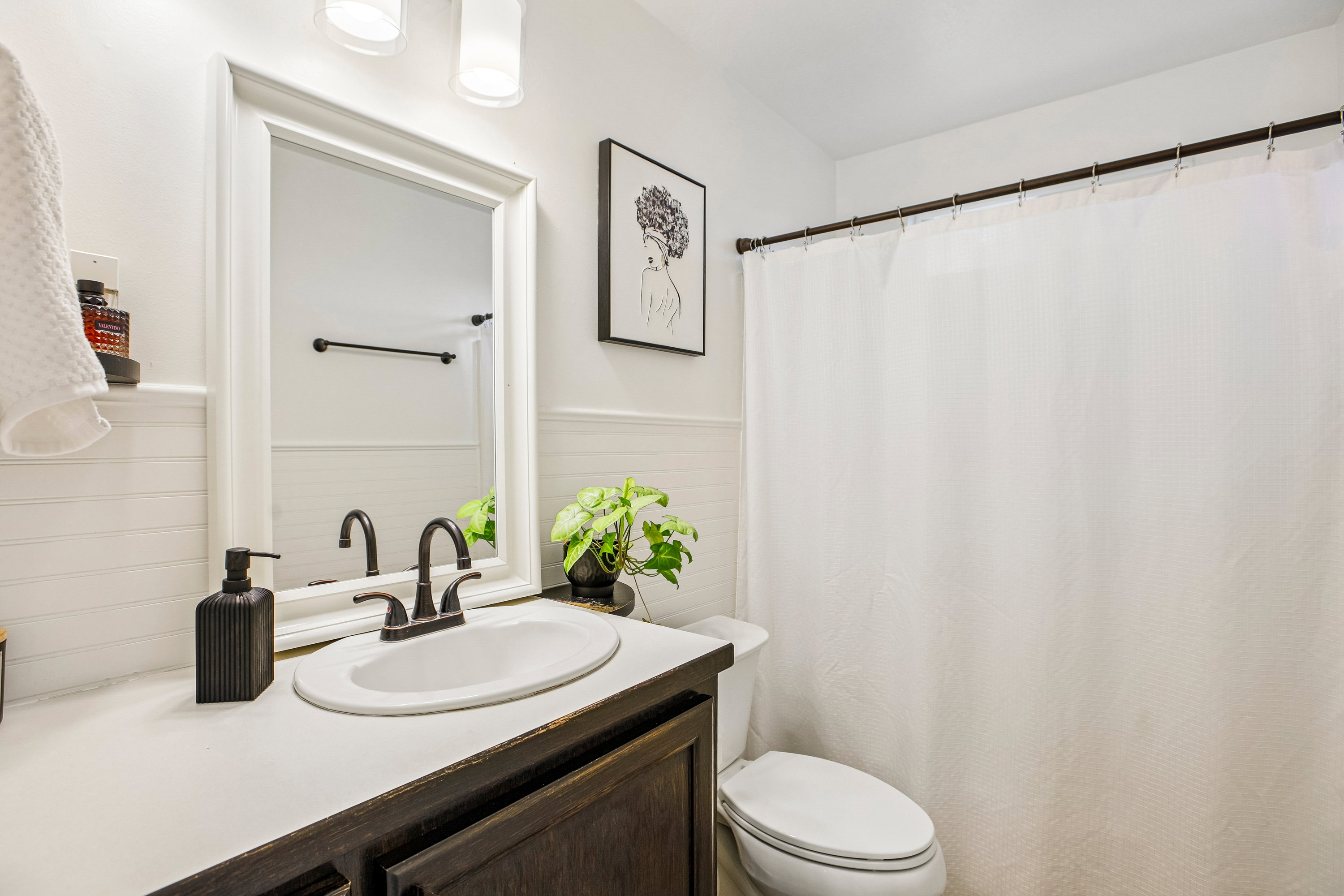 Bathroom featuring a dark wood-finish vanity with a white countertop, an oval undermount sink, and a dark bronze faucet
