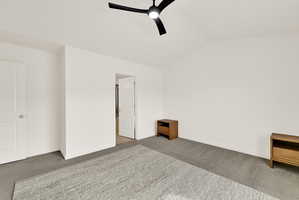 Vaulted ceiling bedroom with a modern black ceiling fan, white walls, and gray carpeting