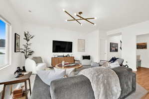 Bright living space featuring a contemporary chandelier, large windows, and light wood-finish flooring