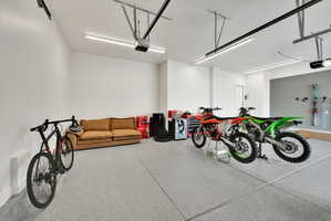Spacious garage featuring white walls, concrete flooring, overhead lighting, and track-mounted storage