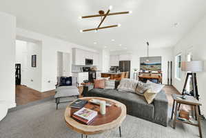 Open concept living area featuring wood-finish flooring, a contemporary chandelier, white walls, and recessed lighting