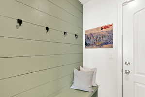 Shiplap accent wall featuring integrated coat hooks and a built-in bench