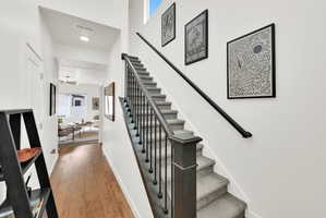 Staircase featuring dark wood newel posts, black metal balusters, and gray carpeted treads